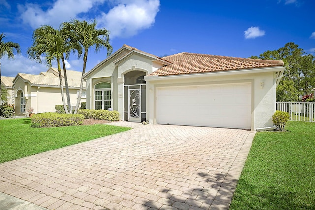 mediterranean / spanish house featuring stucco siding, decorative driveway, a garage, and a front lawn