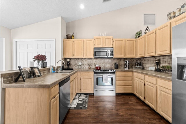 13029 Meadowbreeze Dr, Wellington, FL 33414 - kitchen with stainless steel appliances, vaulted ceiling, light brown cabinetry, and a sink
