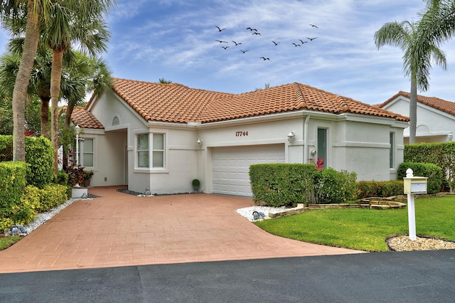 17744 Candlewood Ter, Boca Raton, FL 33487 - mediterranean / spanish-style house featuring a front lawn, stucco siding, a tiled roof, an attached garage, and driveway
