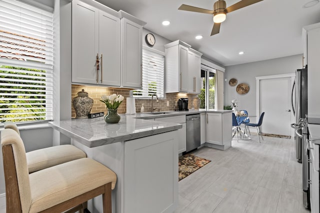 17744 Candlewood Ter, Boca Raton, FL 33487 - kitchen with a peninsula, light stone countertops, tasteful backsplash, a sink, and stainless steel appliances