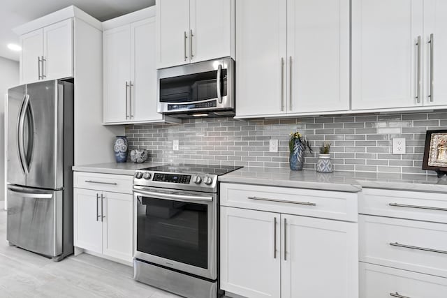17744 Candlewood Ter, Boca Raton, FL 33487 - kitchen with stainless steel appliances, white cabinetry, light wood finished floors, and tasteful backsplash