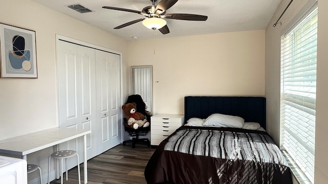 bedroom featuring a ceiling fan, a closet, visible vents, and dark wood-style flooring
