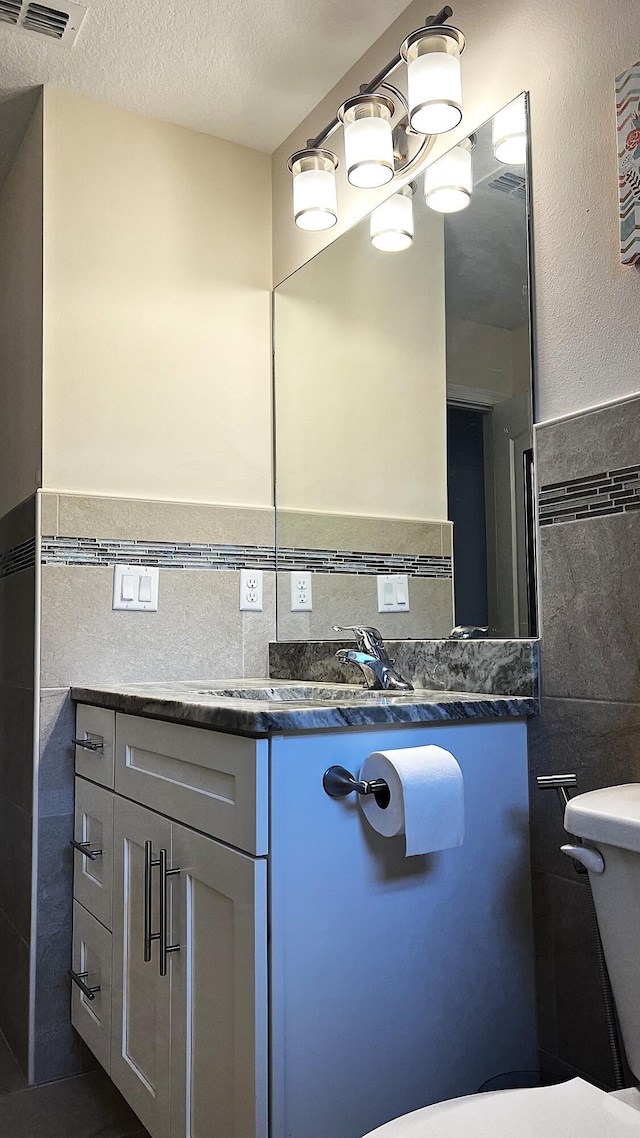 bathroom featuring visible vents, toilet, a textured ceiling, and vanity
