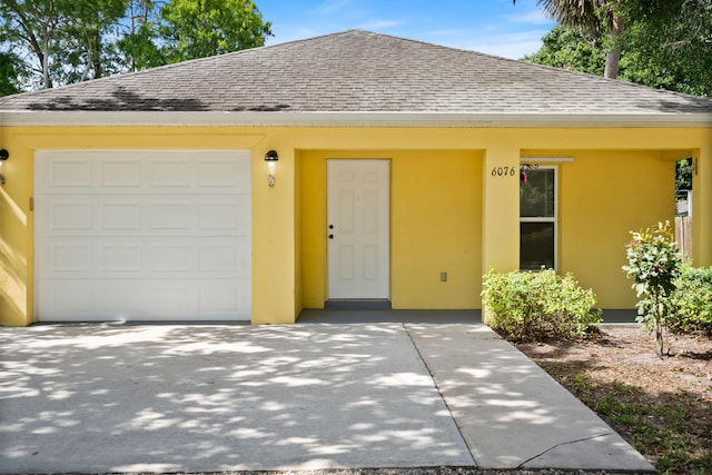 view of front of home featuring a shingled roof, stucco siding, and a garage