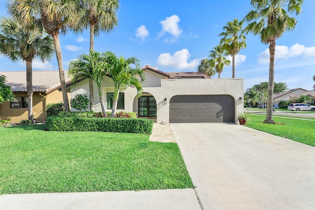 mediterranean / spanish house with a garage, stucco siding, driveway, and a front yard