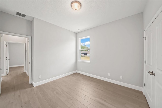 unfurnished bedroom with light wood finished floors, baseboards, and visible vents