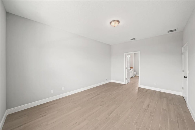 spare room featuring light wood-style floors, visible vents, and baseboards
