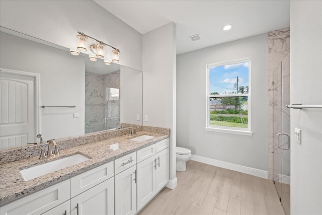 full bath with toilet, a marble finish shower, and a sink