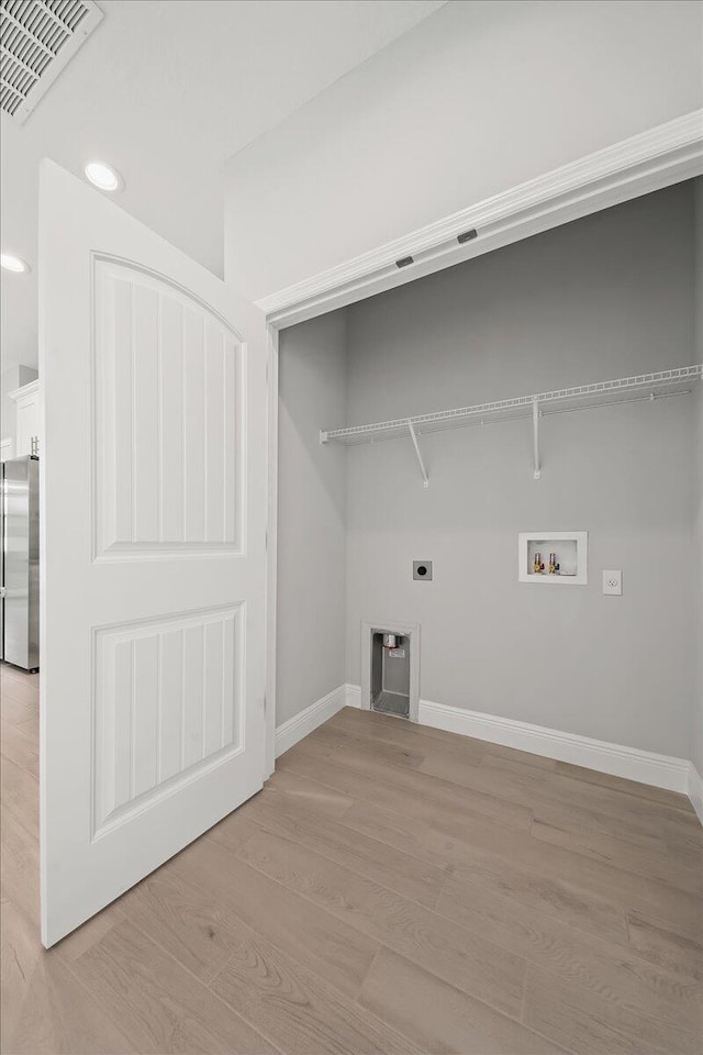 laundry area featuring electric dryer hookup, light wood-style floors, visible vents, baseboards, and laundry area