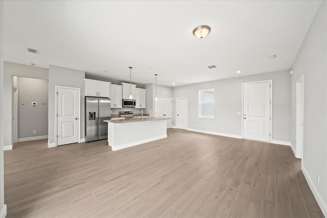 kitchen with an island with sink, stainless steel appliances, visible vents, and a sink