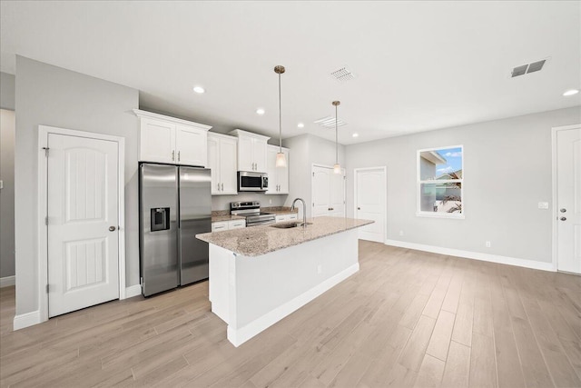 kitchen with an island with sink, stainless steel appliances, visible vents, and a sink