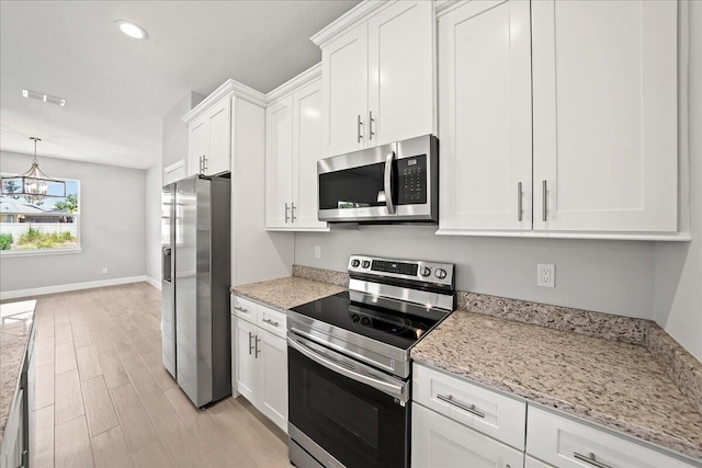 kitchen featuring white cabinets, light wood finished floors, appliances with stainless steel finishes, and an inviting chandelier