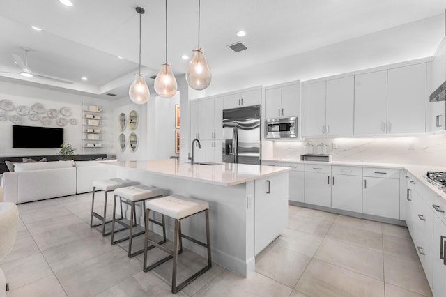 kitchen with appliances with stainless steel finishes, a sink, a kitchen breakfast bar, open floor plan, and light tile patterned flooring