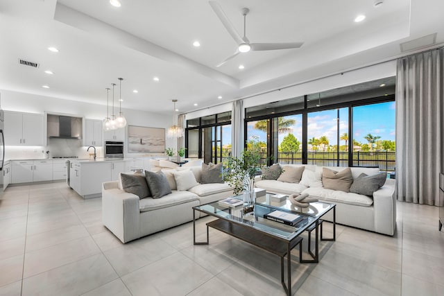 living room with light tile patterned floors, ceiling fan, recessed lighting, and a raised ceiling