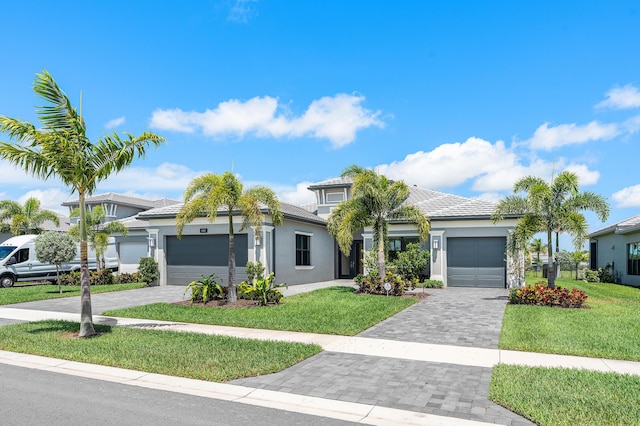 view of front of house featuring an attached garage, decorative driveway, a front lawn, and stucco siding