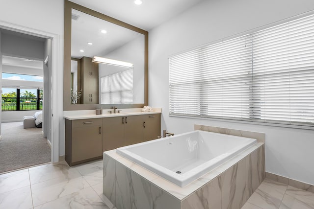 bathroom featuring marble look tile flooring, baseboards, a tub to relax in, vanity, and recessed lighting