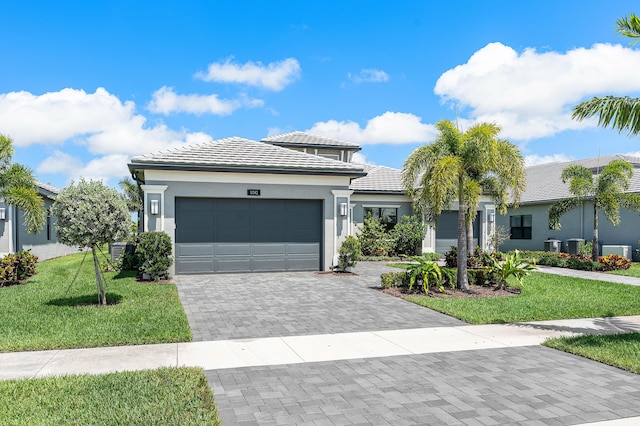 view of front facade with an attached garage, a front yard, decorative driveway, stucco siding, and a tiled roof