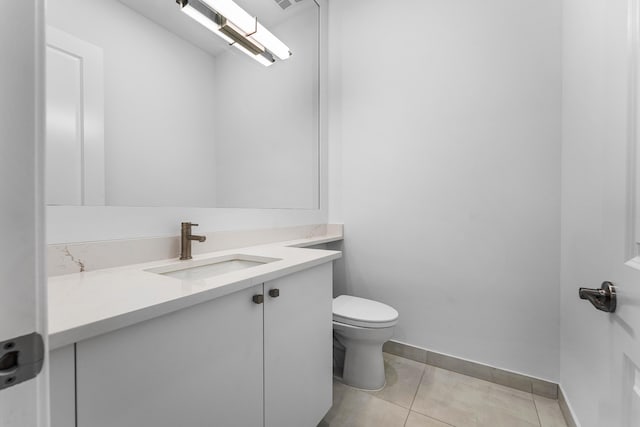 bathroom with toilet, vanity, tile patterned floors, and baseboards