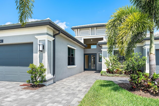 doorway to property with french doors, stucco siding, and an attached garage