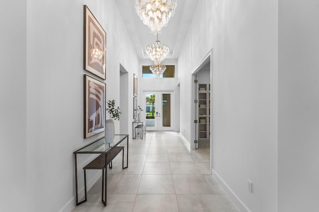 hall featuring a chandelier, light tile patterned flooring, and baseboards