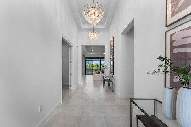 corridor featuring a chandelier, baseboards, and light tile patterned flooring