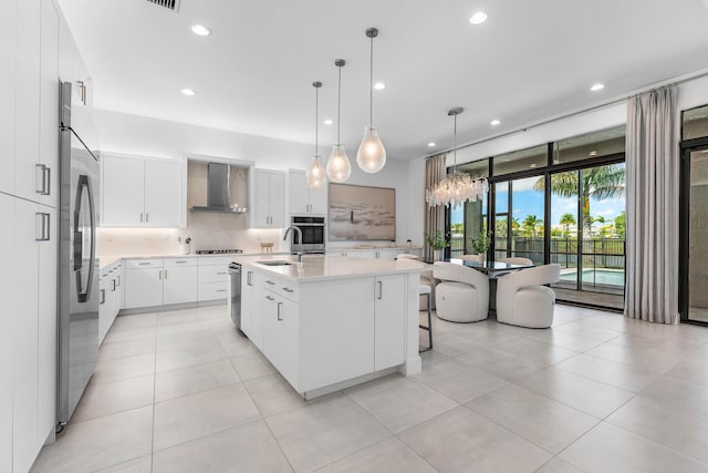 kitchen with stainless steel appliances, wall chimney range hood, decorative backsplash, recessed lighting, and light countertops