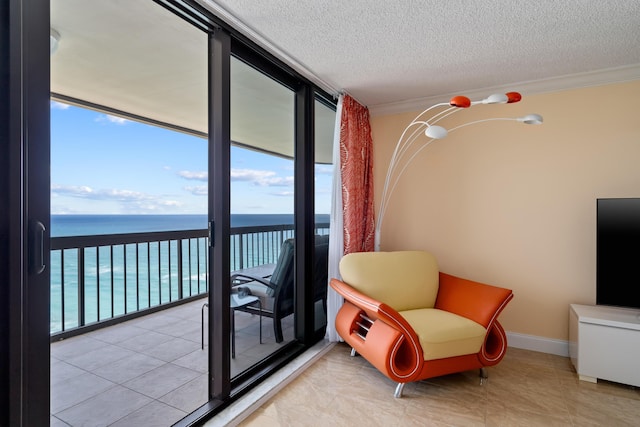 living area with crown molding, a textured ceiling, floor to ceiling windows, a water view, and baseboards
