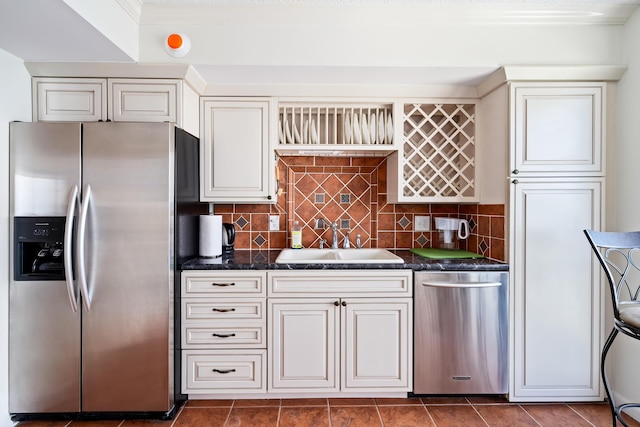 kitchen with dark stone counters, ornamental molding, appliances with stainless steel finishes, and tasteful backsplash