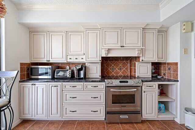 kitchen featuring crown molding, a toaster, stainless steel appliances, backsplash, and tile patterned flooring