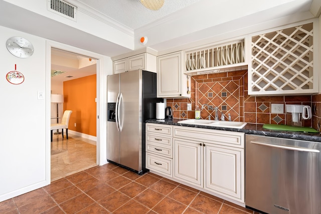 kitchen featuring visible vents, a sink, crown molding, tasteful backsplash, and appliances with stainless steel finishes