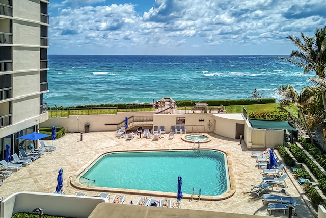 pool featuring fence, a patio, and a water view
