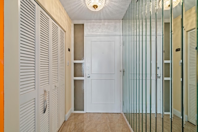 doorway with a textured ceiling and baseboards