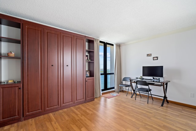 office area with light wood-style flooring, baseboards, a textured ceiling, and floor to ceiling windows