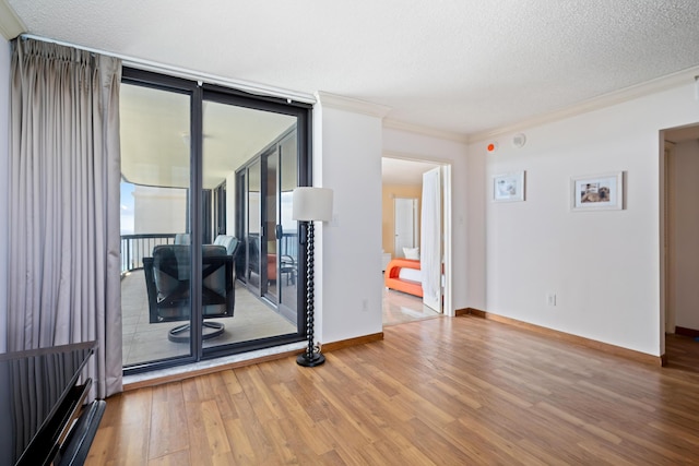 empty room featuring baseboards, crown molding, wood finished floors, and a textured ceiling