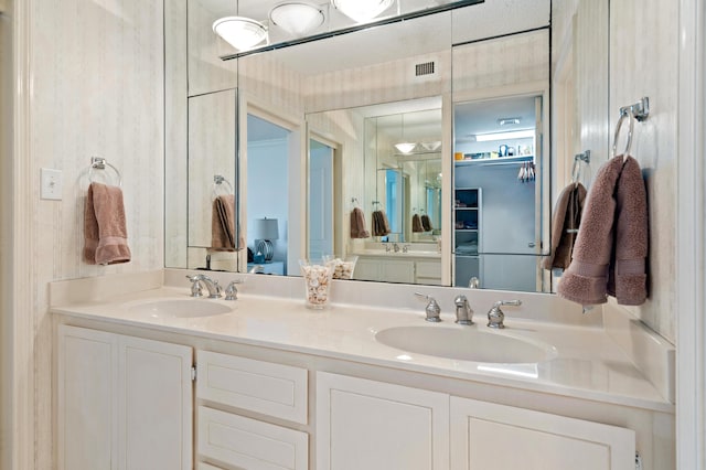 bathroom with visible vents, a sink, and double vanity