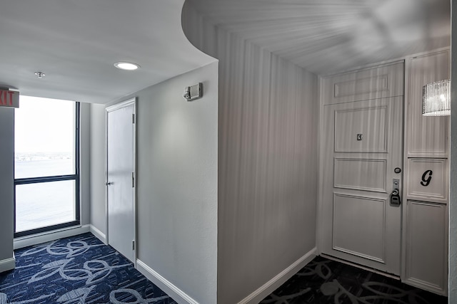 interior space with baseboards and dark carpet