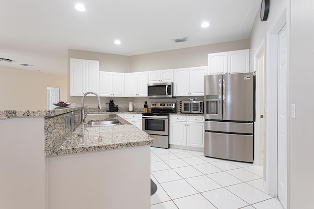 541 NW Pine Sap Pl, Jensen Beach, FL 34957 - kitchen with appliances with stainless steel finishes, a sink, light stone counters, a peninsula, and white cabinets