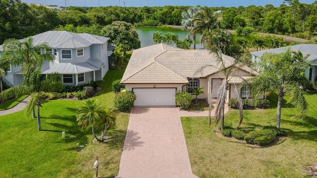 541 NW Pine Sap Pl, Jensen Beach, FL 34957 - view of front facade with an attached garage, decorative driveway, stucco siding, a water view, and a front yard