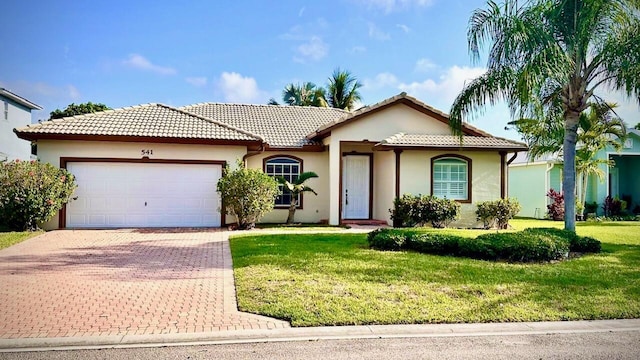 541 NW Pine Sap Pl, Jensen Beach, FL 34957 - mediterranean / spanish home with decorative driveway, an attached garage, a front yard, stucco siding, and a tiled roof