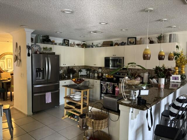 6207 Adriatic Way, West Palm Beach, FL 33413 - kitchen with light tile patterned flooring, dark countertops, appliances with stainless steel finishes, and white cabinetry