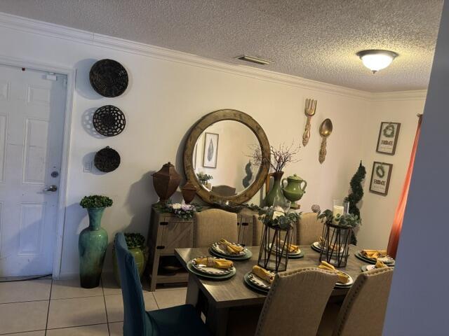 6207 Adriatic Way, West Palm Beach, FL 33413 - dining space with ornamental molding, a textured ceiling, visible vents, and light tile patterned floors