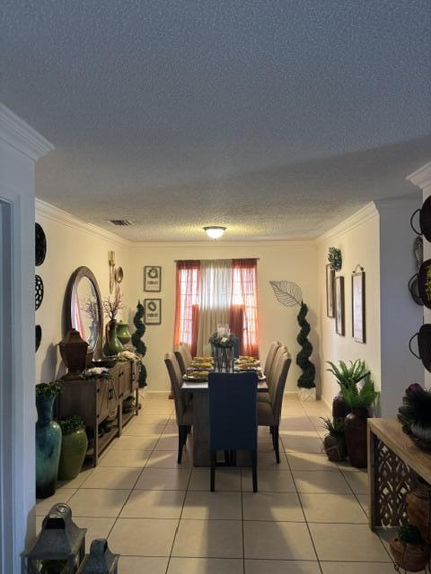 6207 Adriatic Way, West Palm Beach, FL 33413 - dining space with light tile patterned flooring, a textured ceiling, ornamental molding, and visible vents