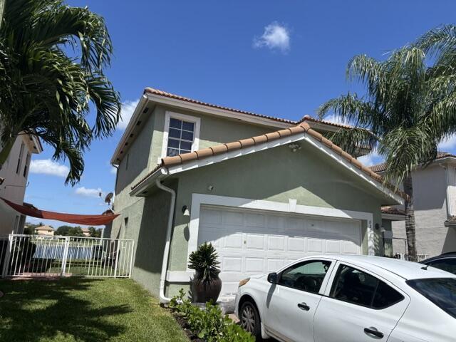 6207 Adriatic Way, West Palm Beach, FL 33413 - view of home's exterior featuring fence, a tiled roof, a garage, and stucco siding