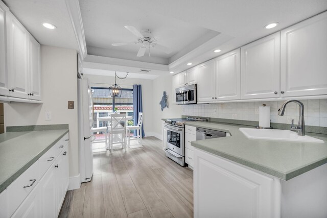 kitchen featuring a sink, ceiling fan with notable chandelier, tasteful backsplash, and stainless steel appliances