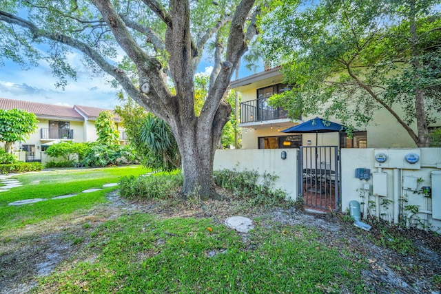 view of yard featuring a gate, a fenced front yard, and a balcony