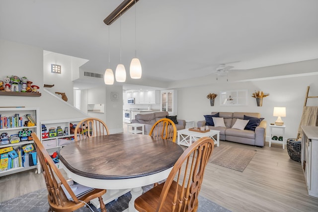 dining room with a ceiling fan, visible vents, and light wood-style flooring