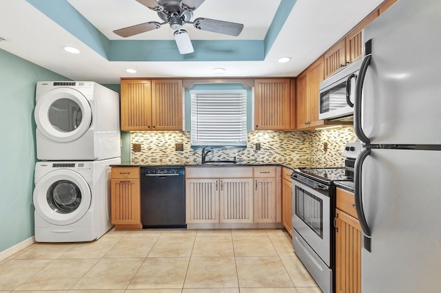 301 Lake Shore Dr Unit 503, Lake Park, FL 33403 - kitchen with dark countertops, a sink, stacked washing maching and dryer, backsplash, and appliances with stainless steel finishes