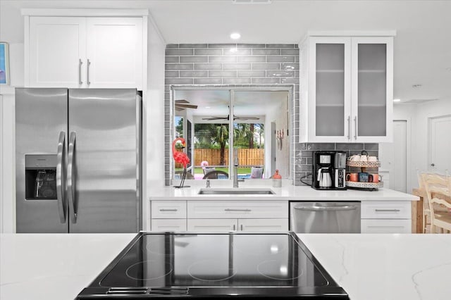 509 Oak Ter, Jupiter, FL 33458 - kitchen featuring a sink, glass insert cabinets, white cabinetry, backsplash, and appliances with stainless steel finishes