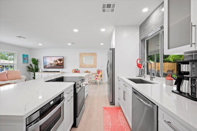 509 Oak Ter, Jupiter, FL 33458 - kitchen with stainless steel appliances, a sink, light wood-type flooring, visible vents, and a kitchen island
