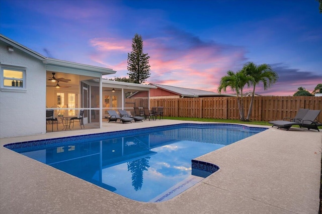 509 Oak Ter, Jupiter, FL 33458 - pool at dusk featuring a fenced in pool, a ceiling fan, fence, a patio area, and a sunroom